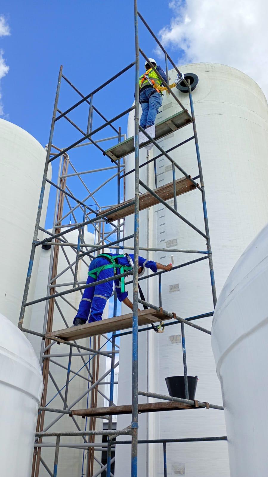 Homens trabalhando em pintura de tanque industrial